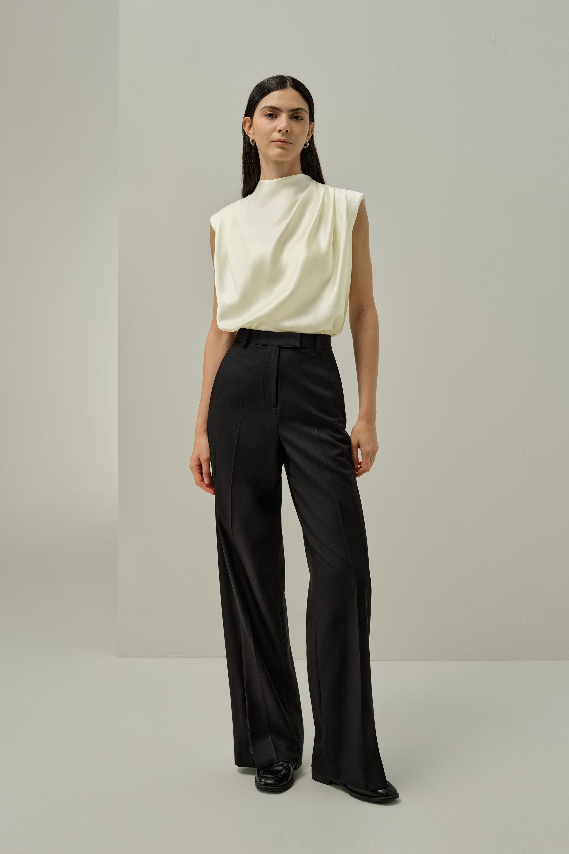 Ivory satin sleeveless draped blouse with high neckline and gathered folds