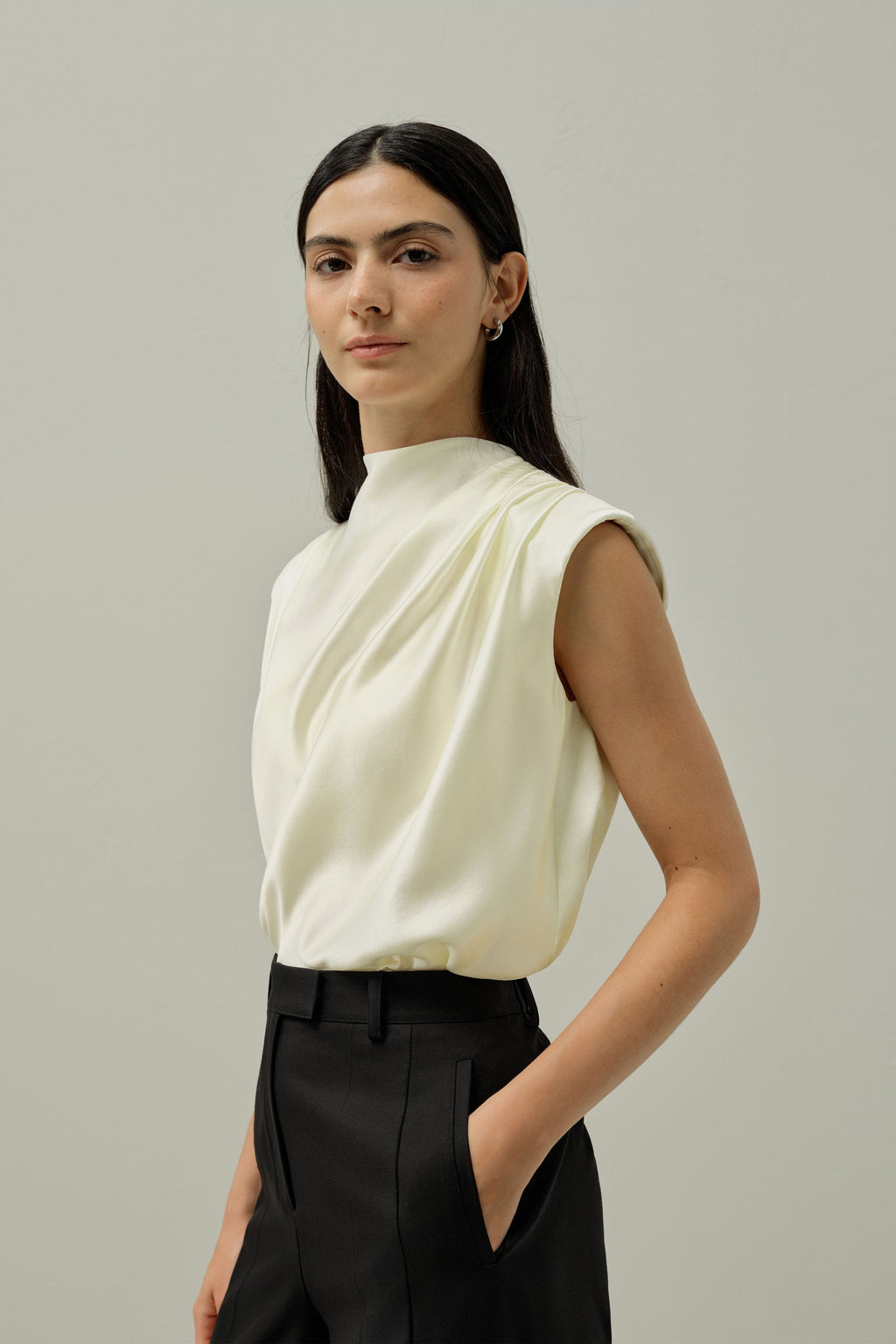 Ivory satin sleeveless blouse with high neckline and soft draped shoulder