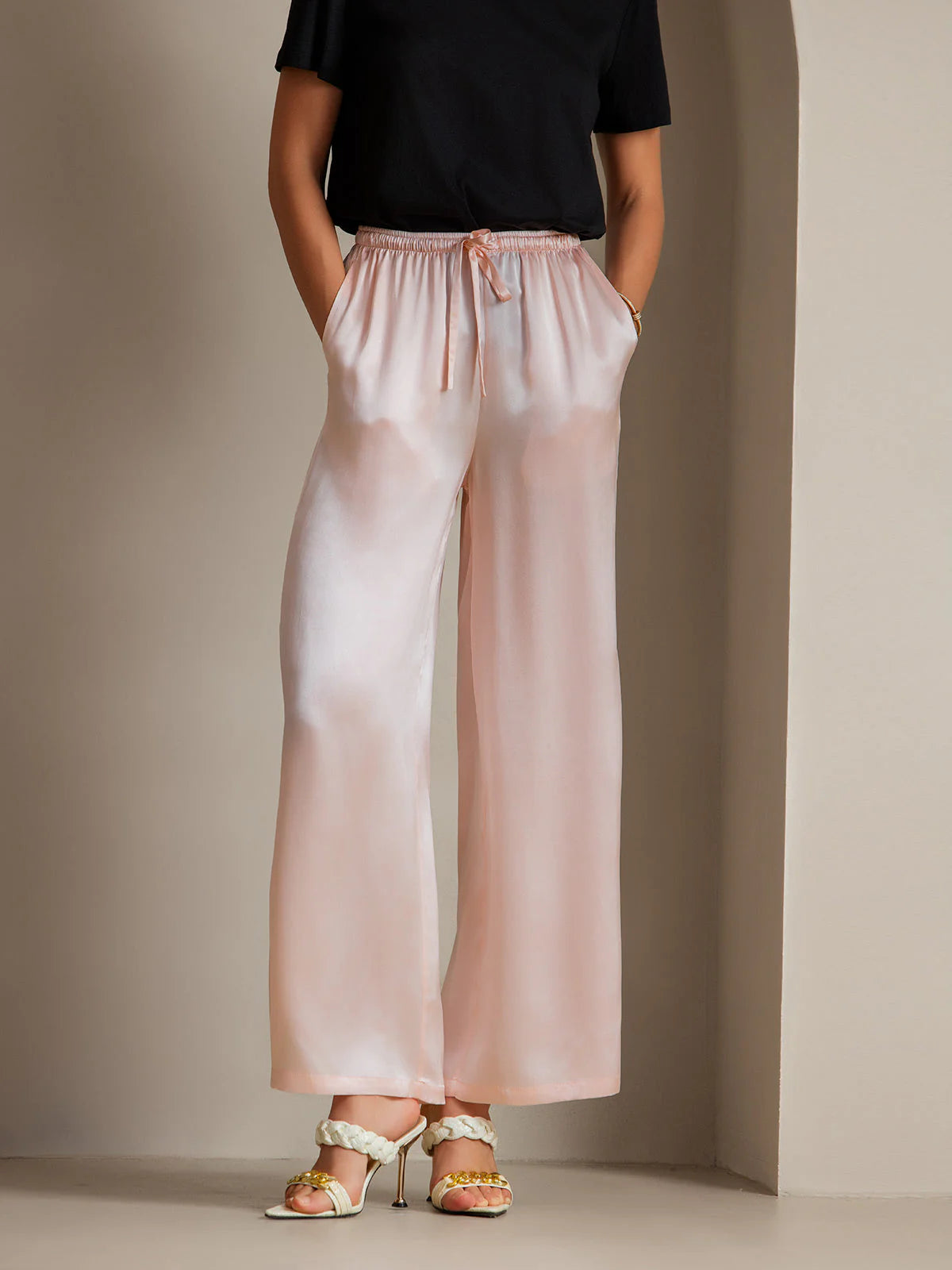 Pink silk relaxed pants with elastic drawstring waist and wide, flowy legs