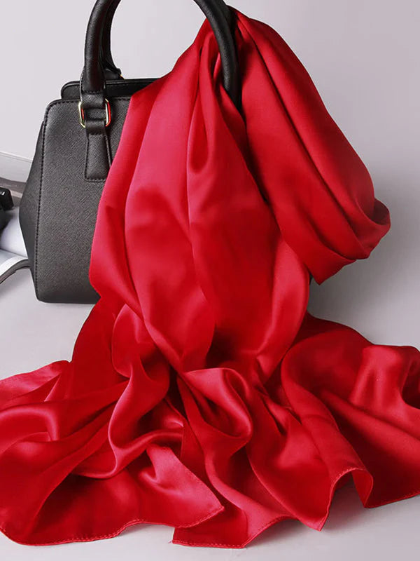 Red satin scarf/shawl with flowing folds, draped around a bag handle