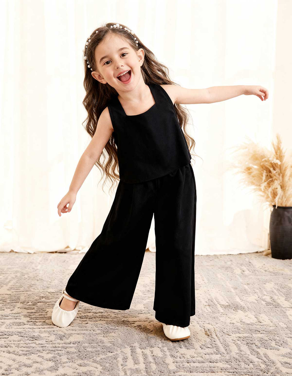 Girls black sleeveless top and wide-leg pants 2-piece set, playful arms-out pose