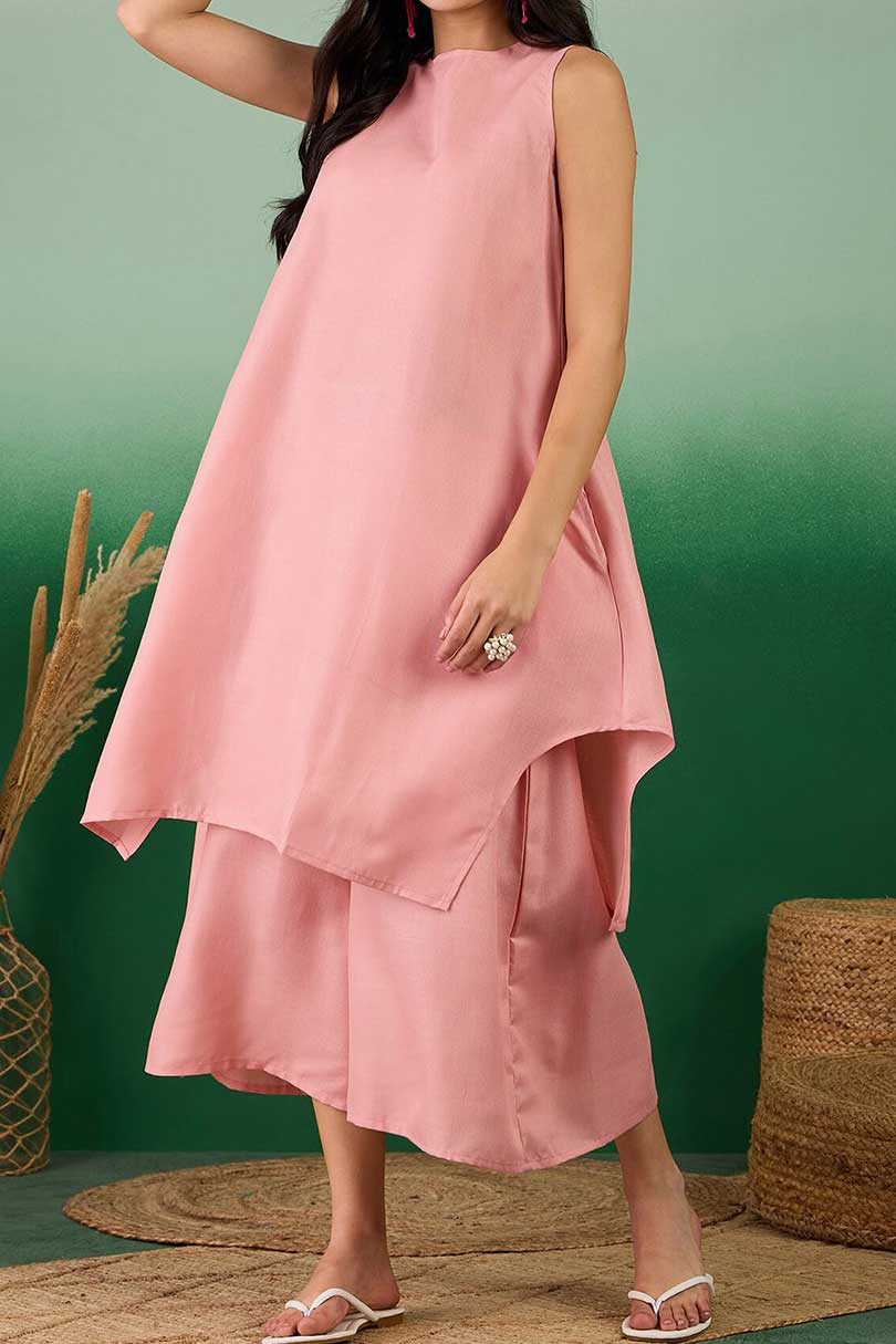 Coral linen sleeveless tunic dress with layered hem, paired with midi pants